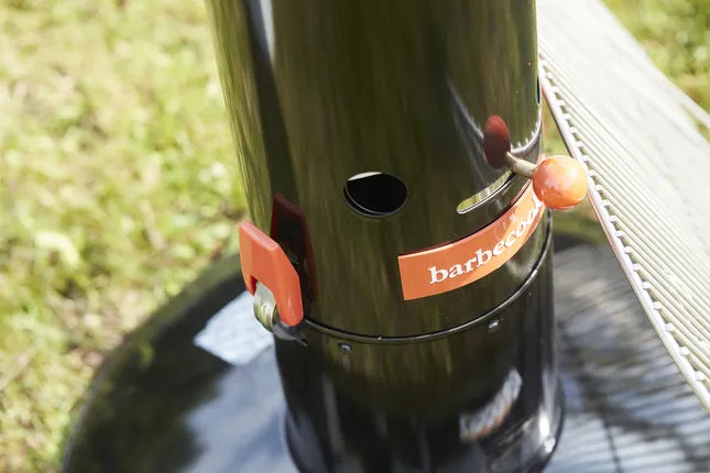 Zwarte houtskoolbarbecue met oranje regelhendel en ventilatiegaten aan de zijkant