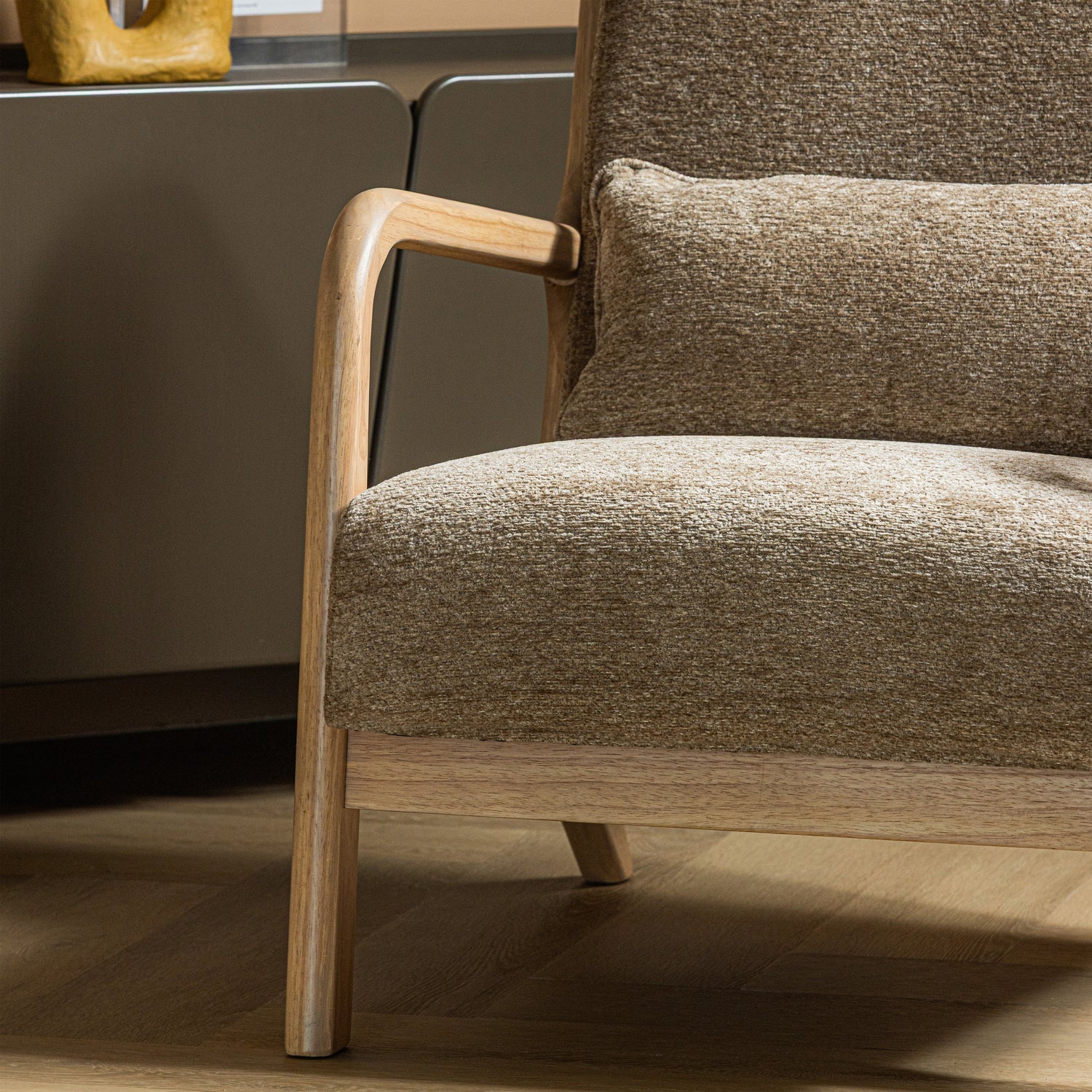 Zandkleurige chenille fauteuil met houten armleuning en zijframe.