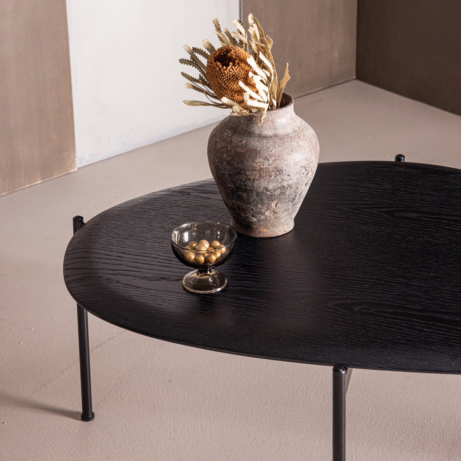 Zwarte ovale salontafel met rond houten blad en vier metalen poten