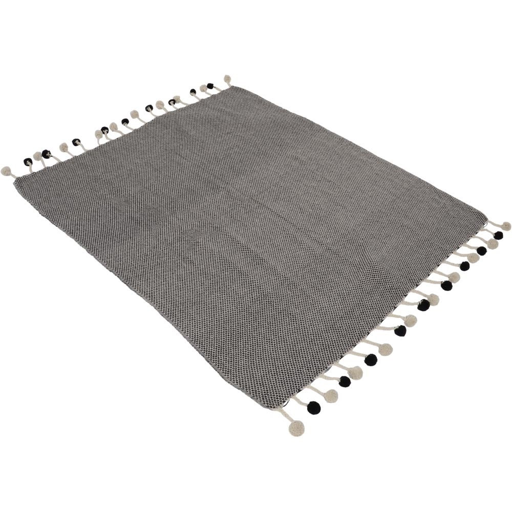Grijze plaid met pompons langs de randen, gevouwen