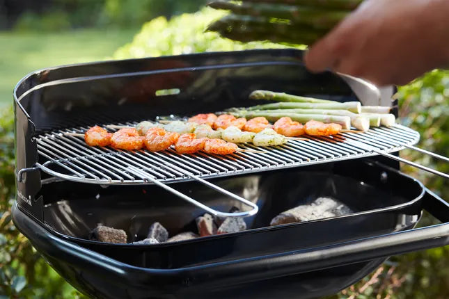Zwarte houtskoolbarbecue met grillrooster en gegrilde stukken boven de kolen