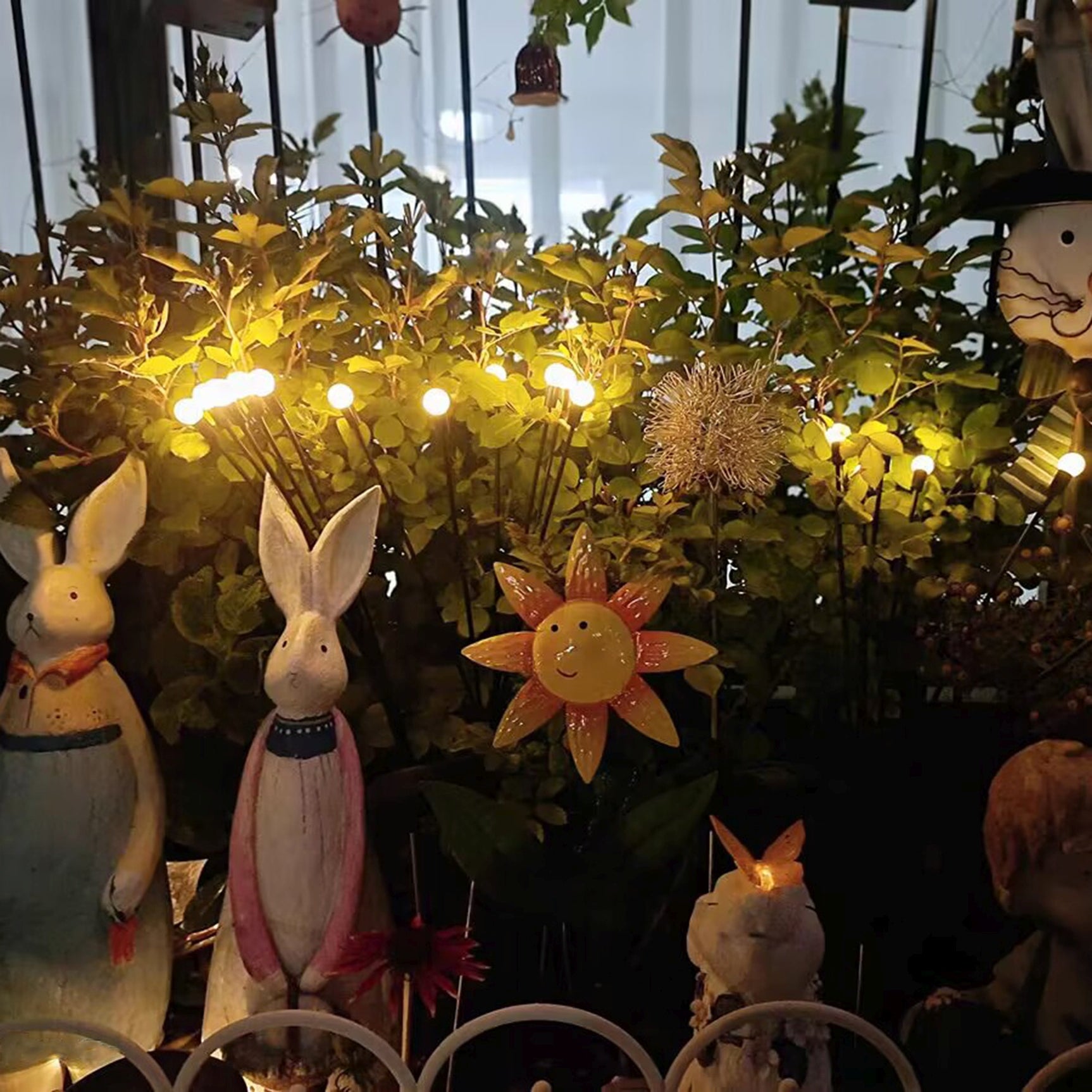 Zonne-energie tuinpriklamp met brandende ronde lampjes tussen beplanting