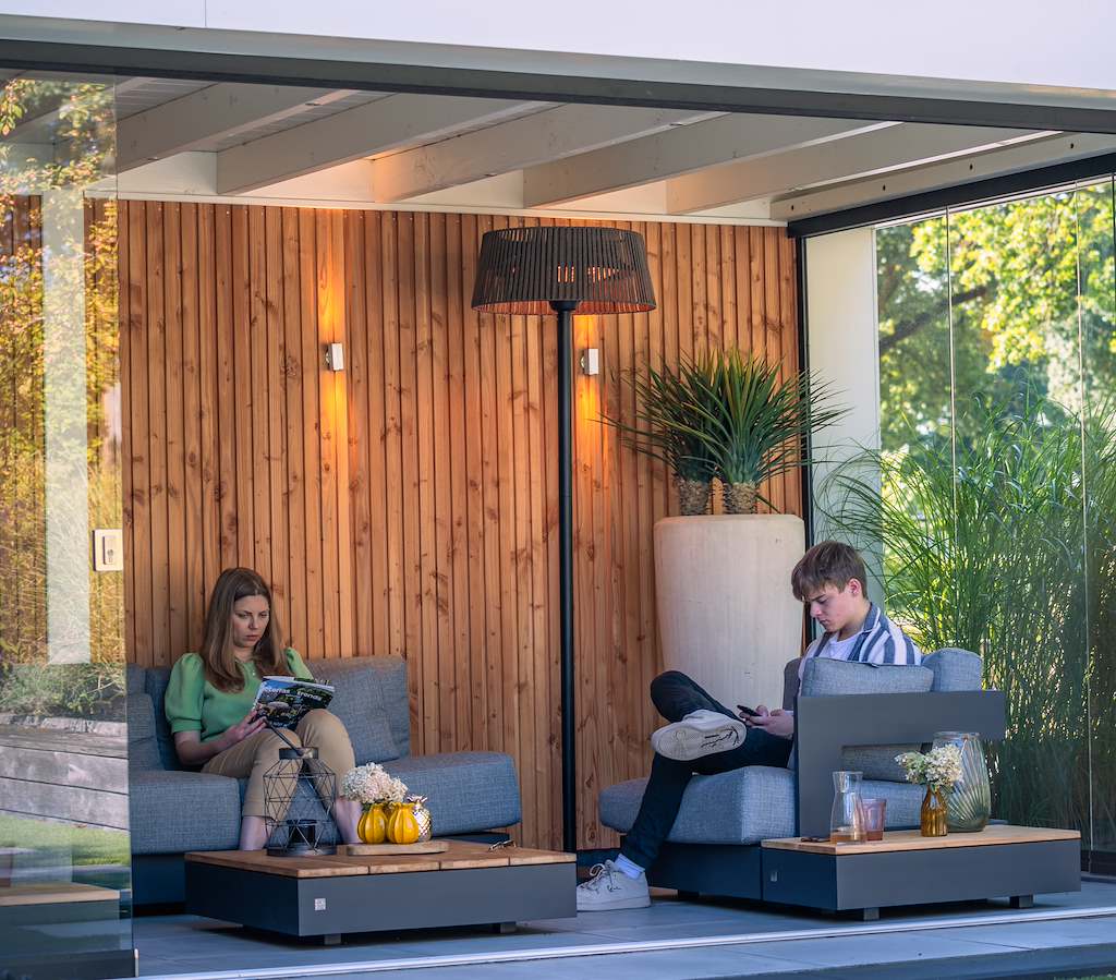 Terrasverwarmer staand toestel met brander in ronde kap boven loungeset.