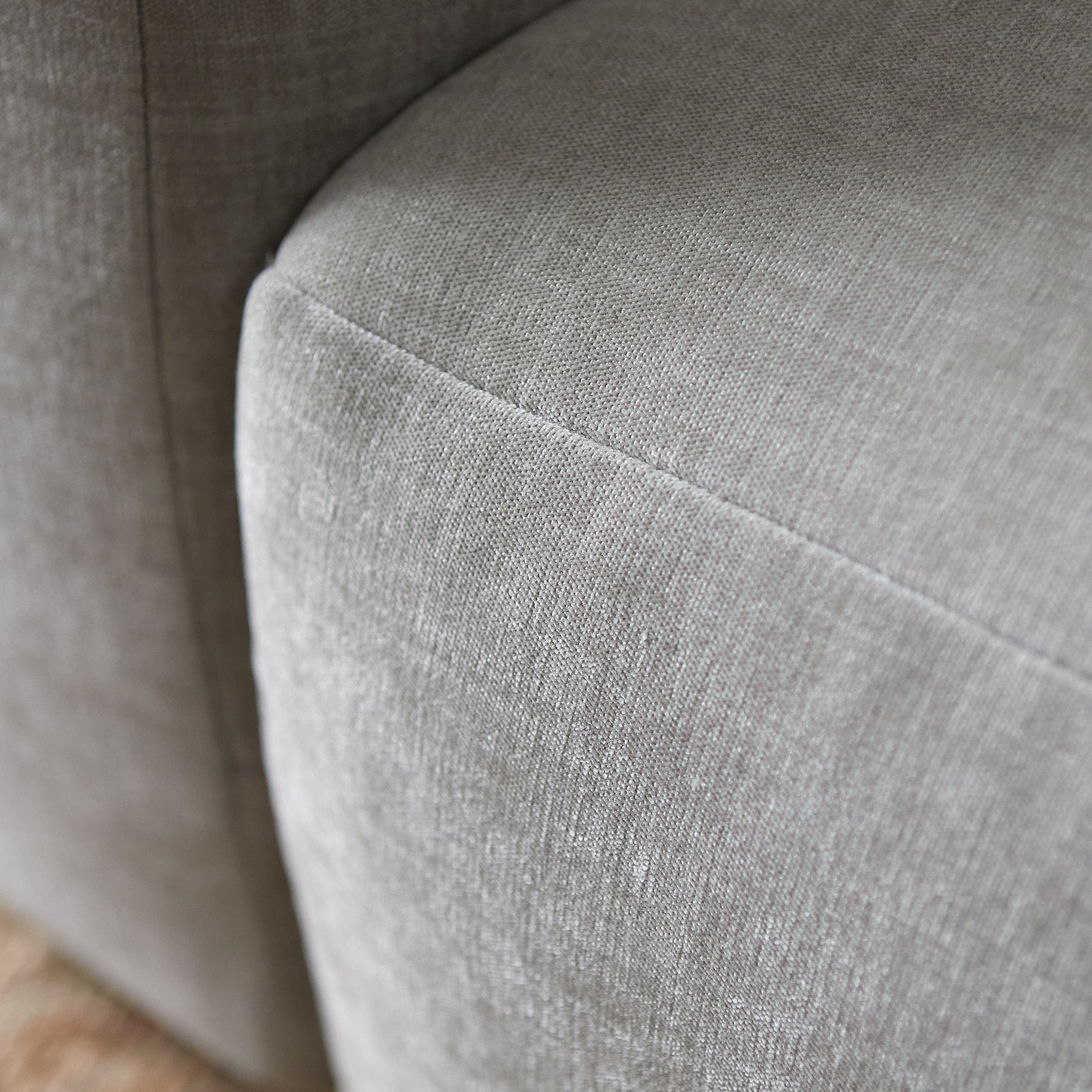 Close-up van afgeronde chaise-rand en fijn geweven lichtgrijze bekleding