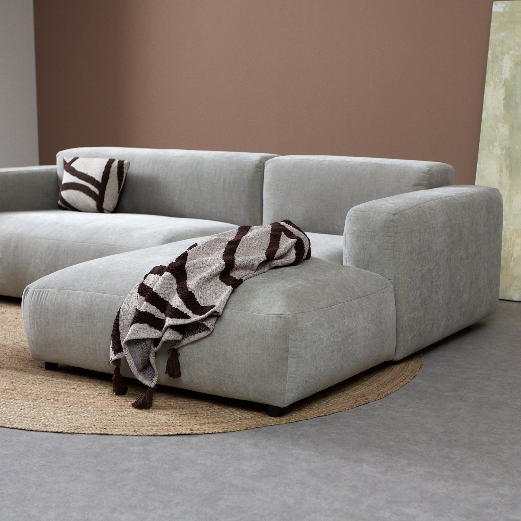 Hoekbank met chaise rechts in lichtgrijs, met opgevouwen deken en kussen