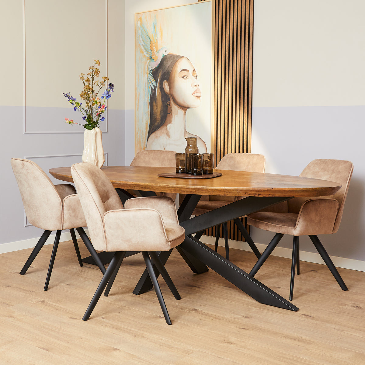 Ovale eettafel met honingkleurig houten blad en zwarte X-poten, in combinatie met stoelen