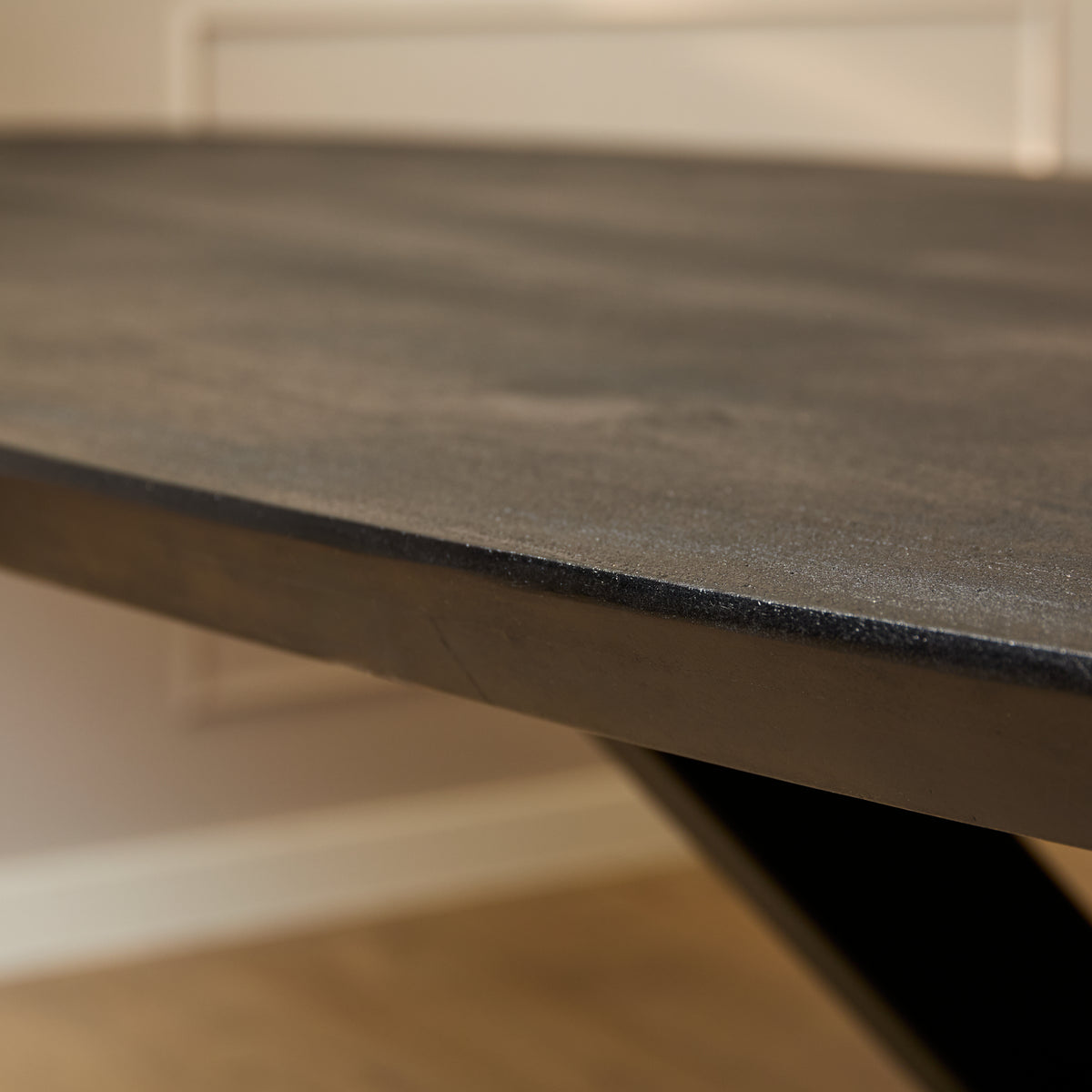 Close-up van de ovale tafelrand met donker blad en zwart metalen steun