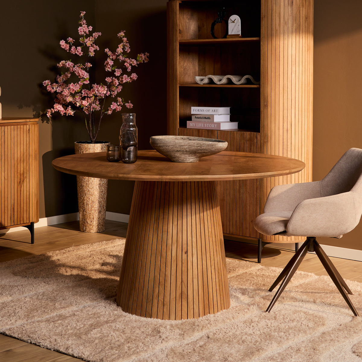 Ronde eettafel met naturel houtnerf blad en conische ribbelpoot, stoel zichtbaar