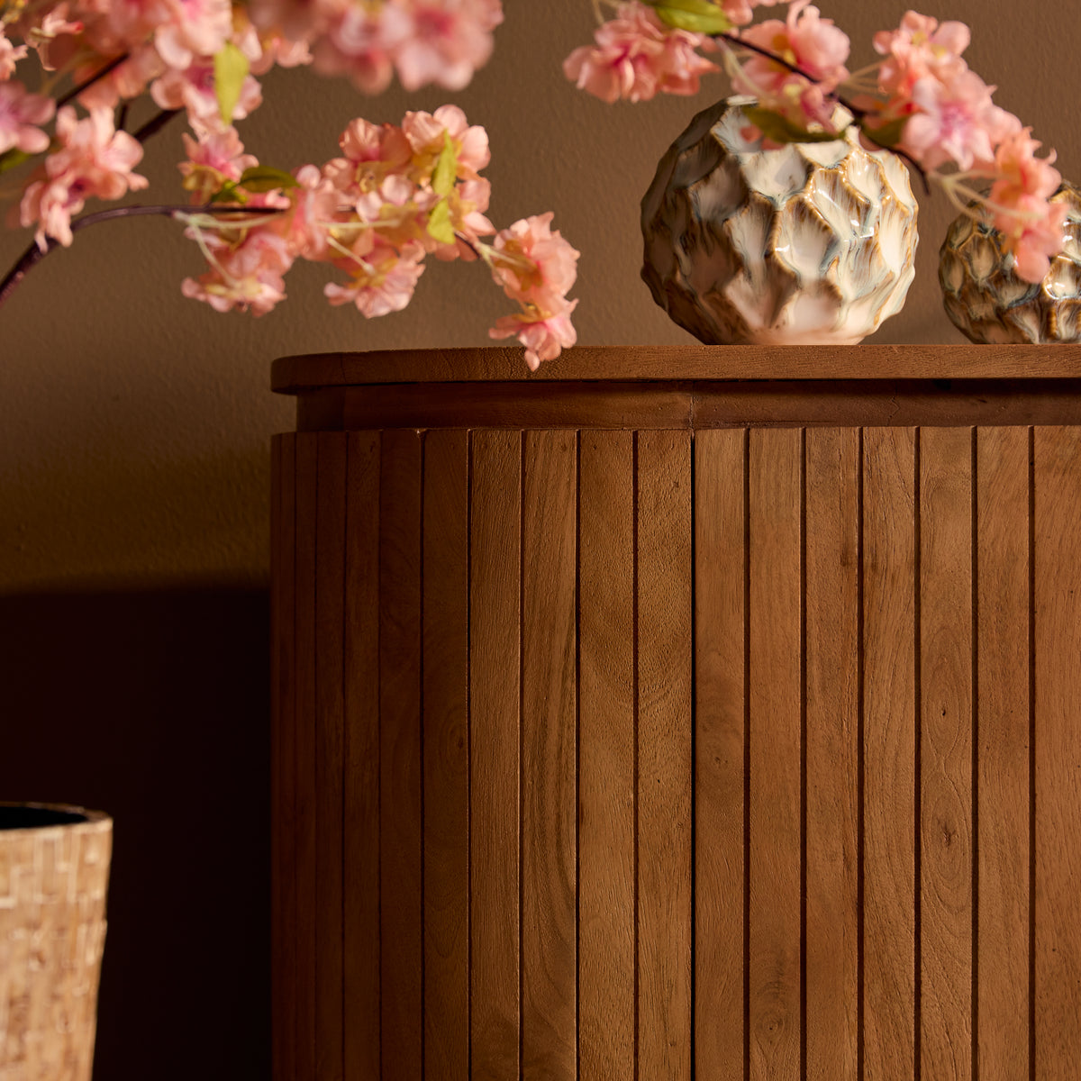 Naturel houten front van kabinetkast met verticale groeven en ronde bovenrand.