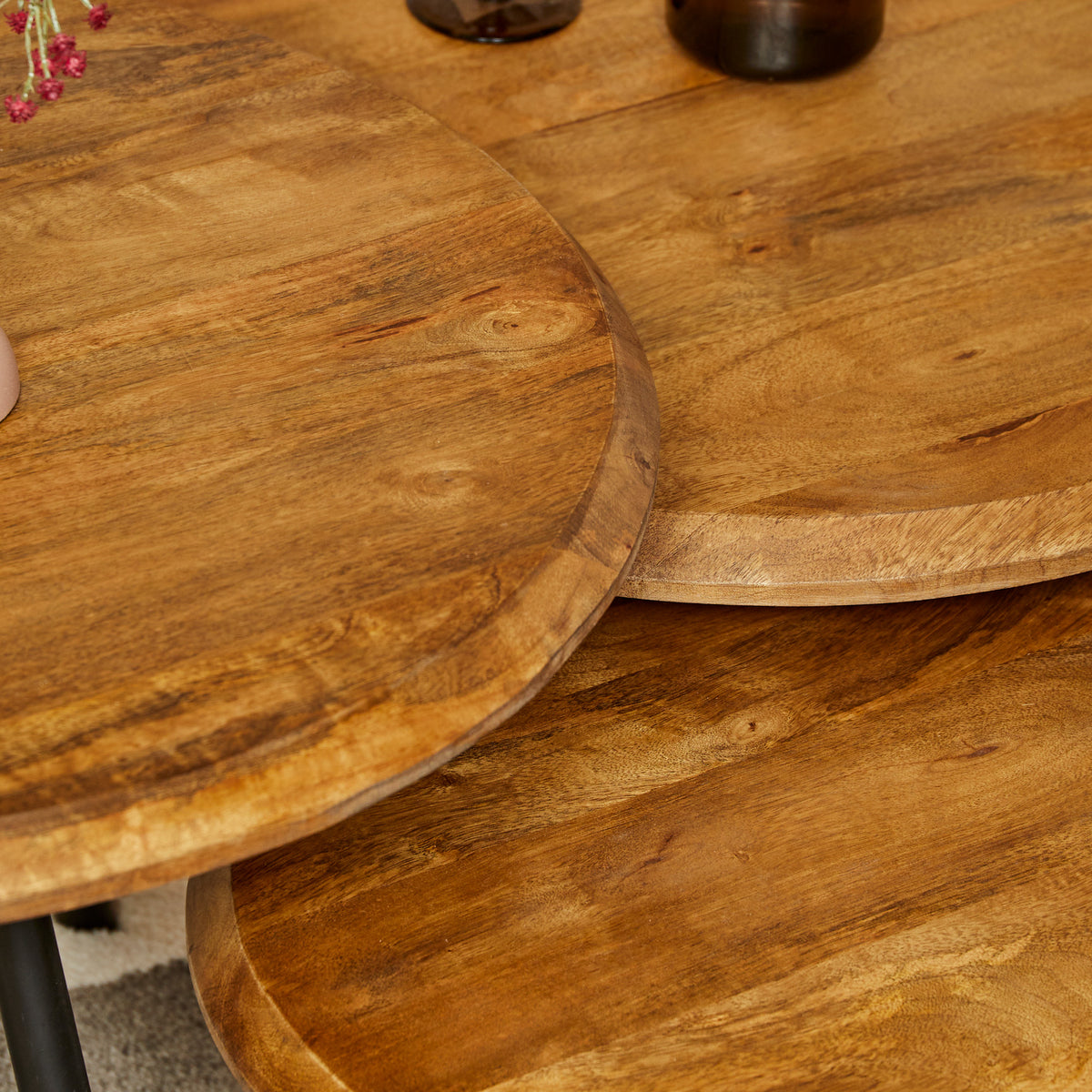 Close-up van rond houten salontafelblad met houtnerf en zwarte poot