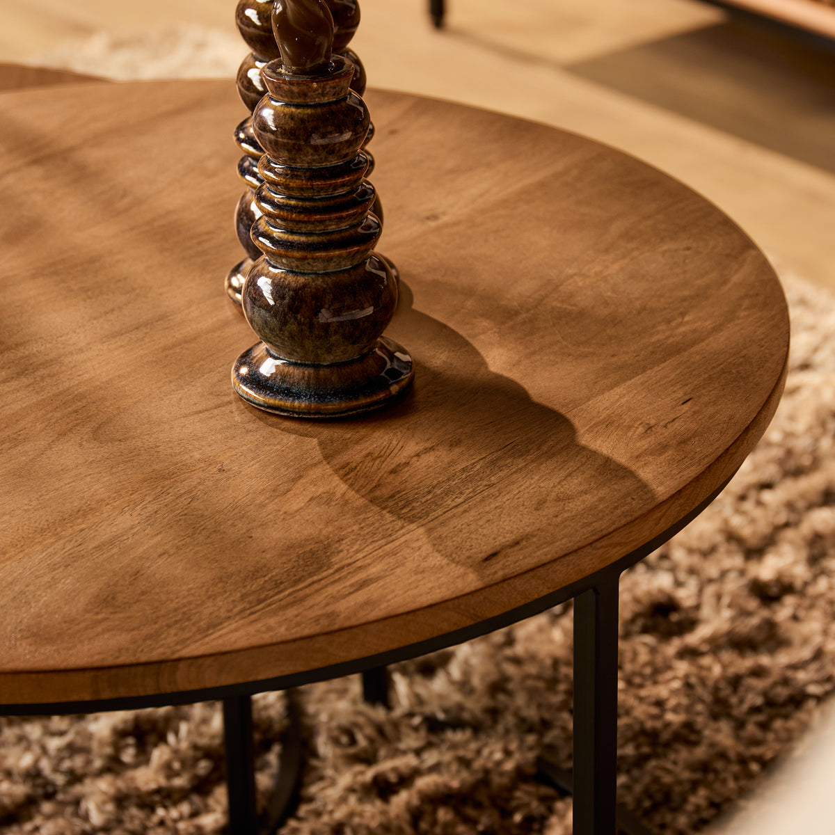 Rond naturel houten tafelblad met randdetails en zwart metalen poten, salontafel