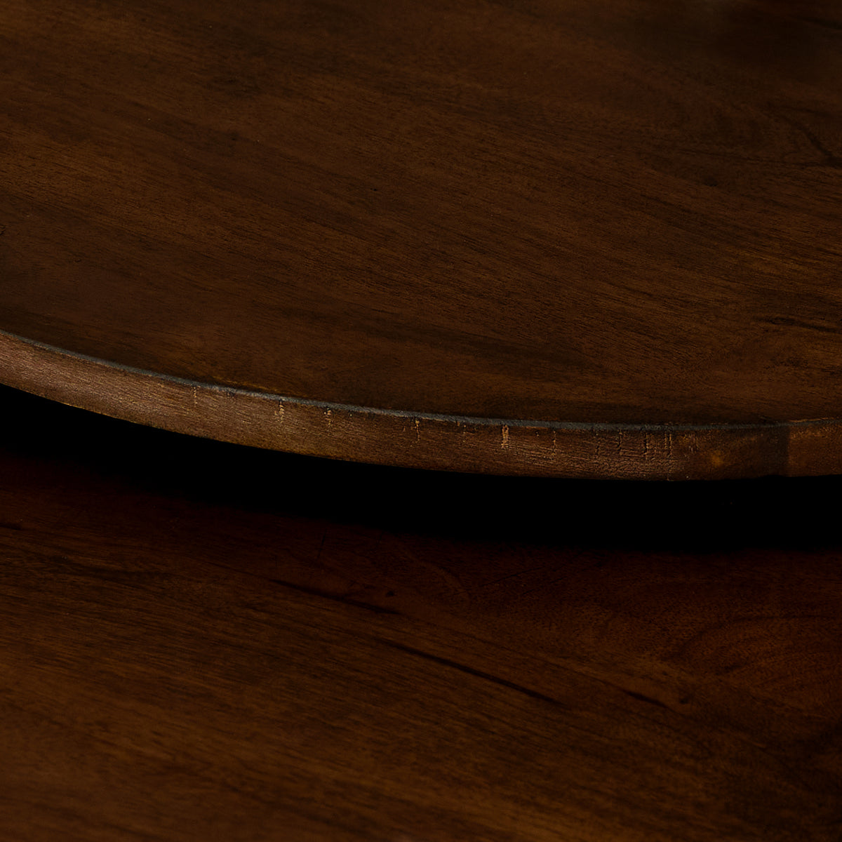 Donkerbruine houten bladrand van een ronde salontafel met zwarte metalen frame