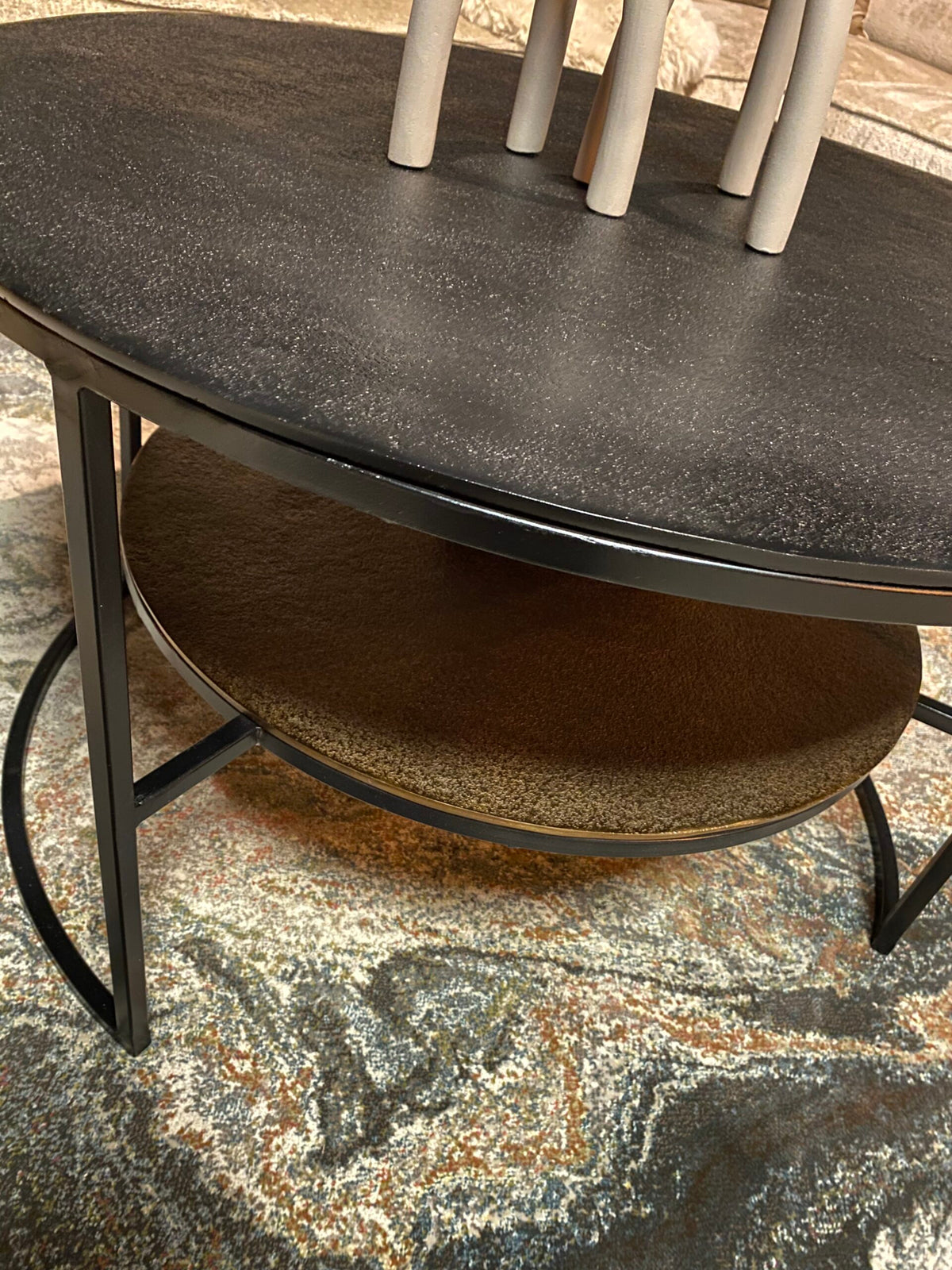 Zwarte salontafel met afgerond blad en metalen frame, ronde onderplank onder tafel