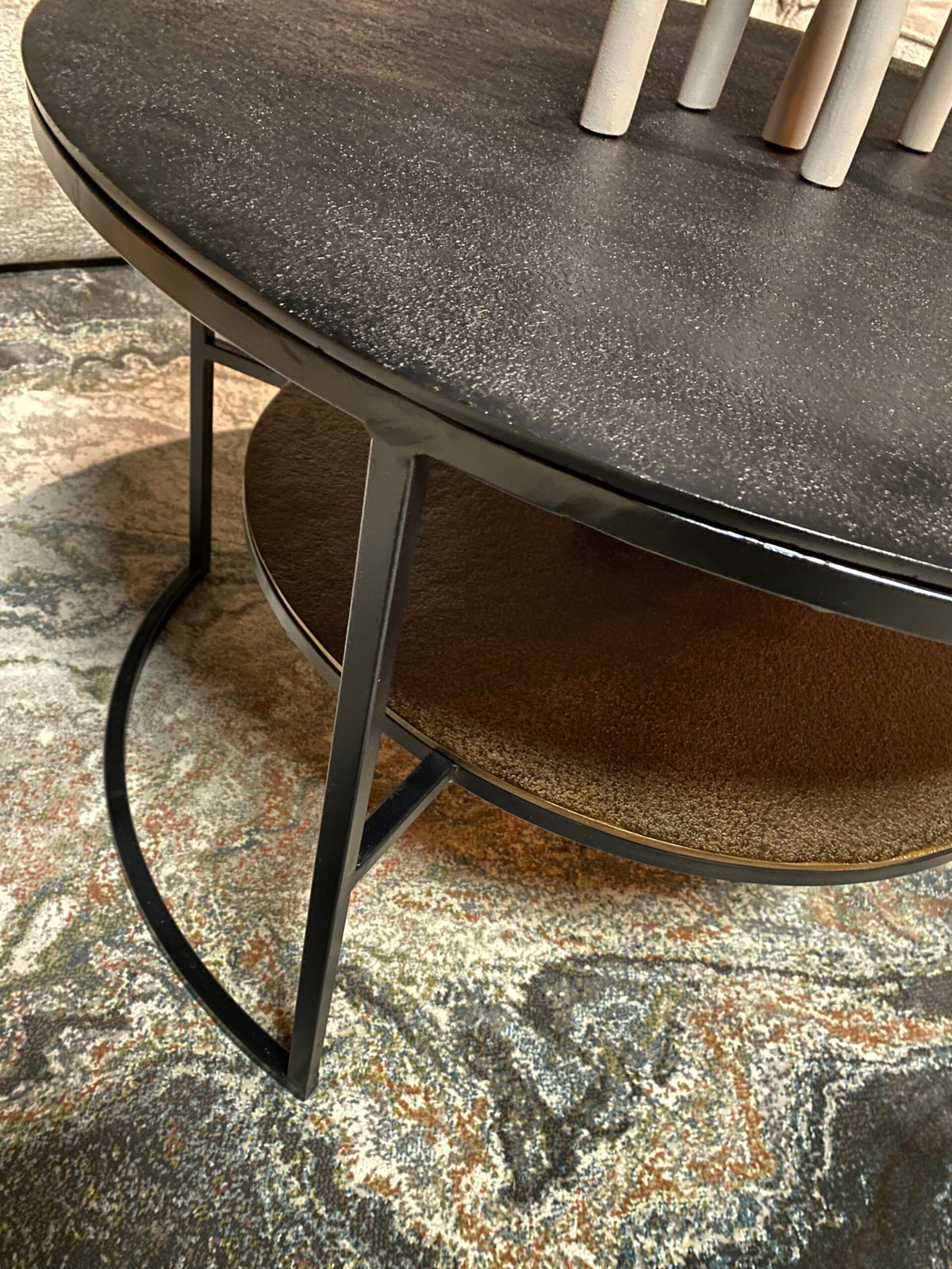 Zwarte ronde salontafel met metalen onderstel en gebogen zwarte poot, onderplank