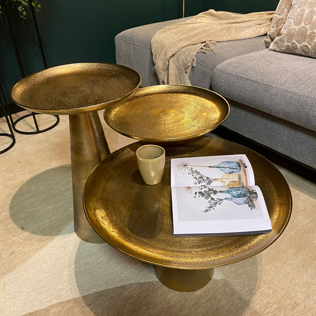 Ronde goudkleurige salontafel met twee losse bladen, mok en open tijdschrift