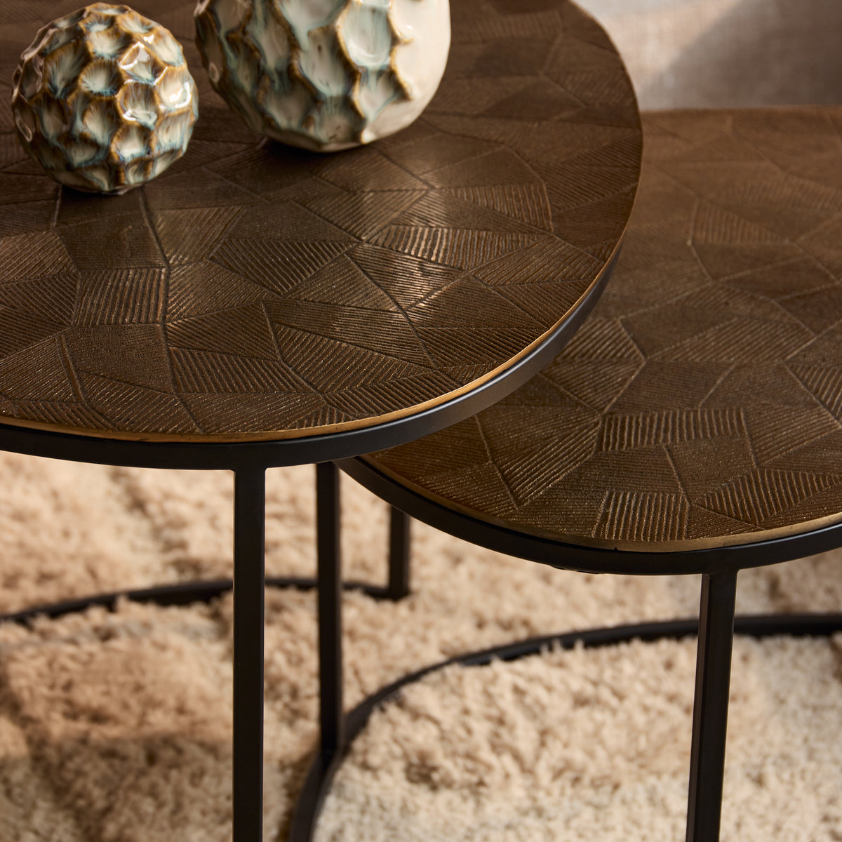 Ronde salontafel met donkerbruin blad met geometrisch reliëf en zwarte metalen poot