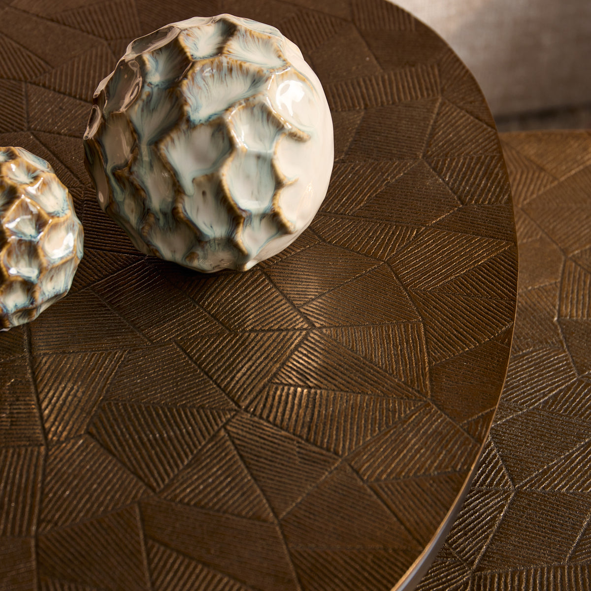 Ronde salontafel met donkerbruin blad en geometrisch reliëf, zwarte metalen poot