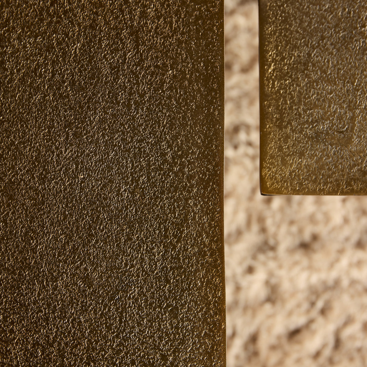 Hoekdetail van goudbruine salontafel met glanzende metalen rand en textuur