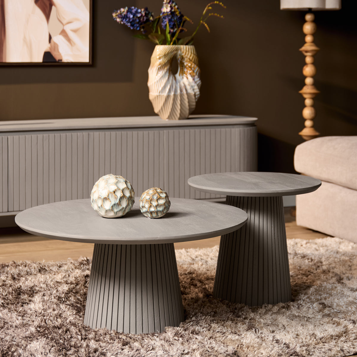 Twee ronde salontafels met grijs blad en geribbelde kolompoot in taupe tint