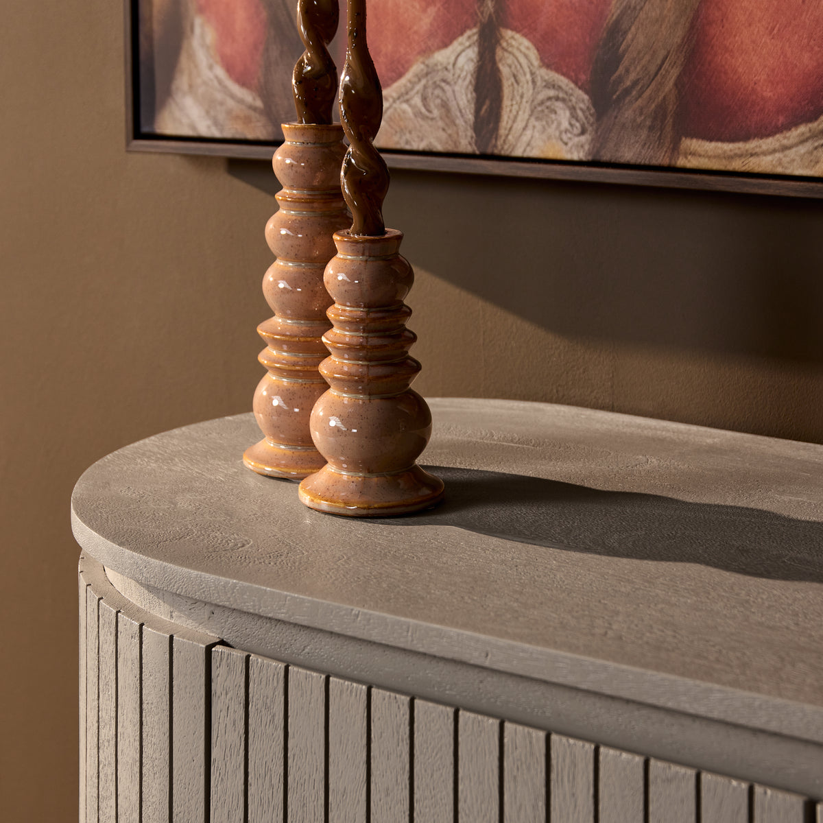Taupe lage kast met verticaal gestreepte panelen en ronde pootjes, bovenrand zichtbaar.