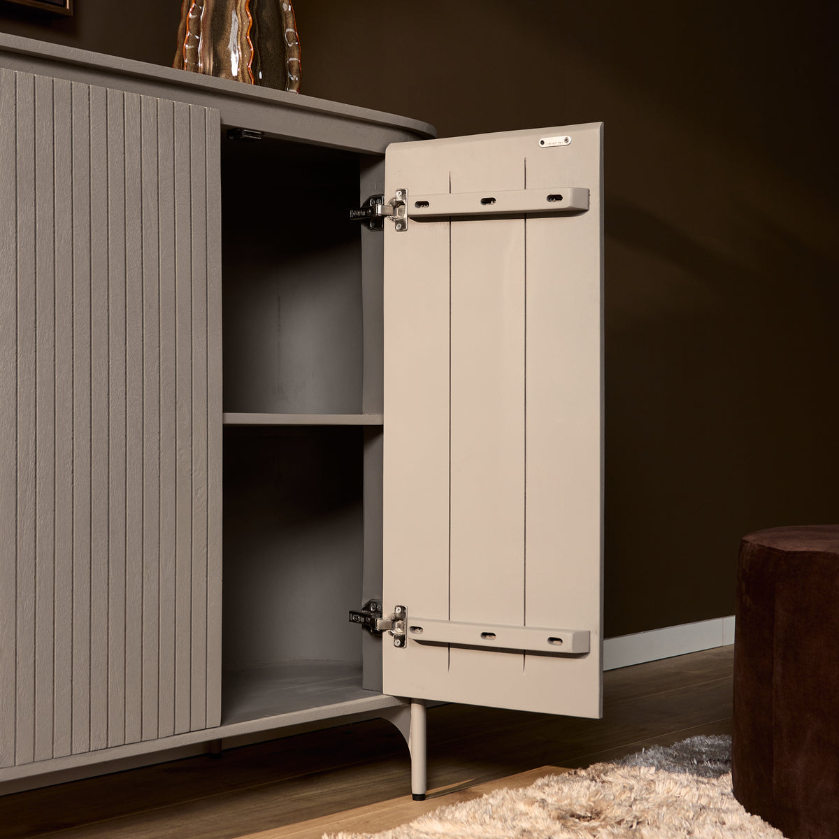 Taupe kast met open scharnierdeur en zichtbare plankruimte, verticaal gestreept front.