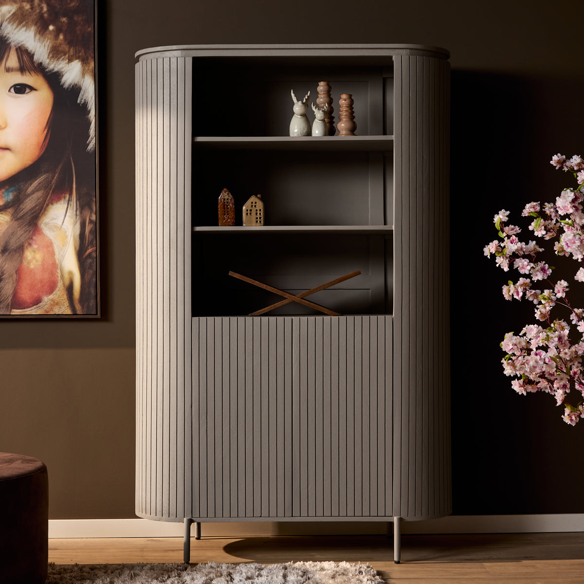 Taupe wandkast met open deur en legplanken; decorstukken staan in het zicht.