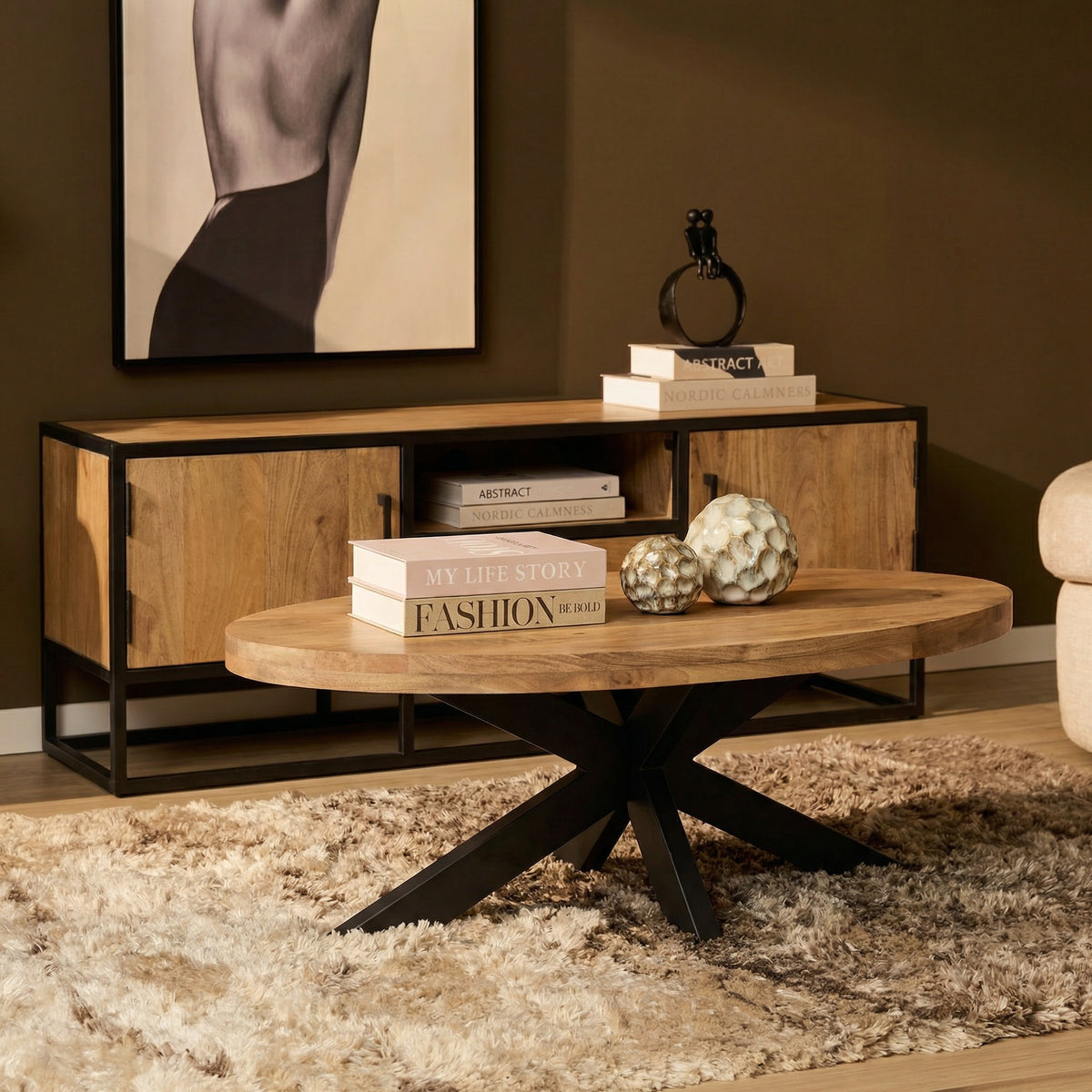 Ovale salontafel met licht eikenhouten blad en zwart metalen frame, met boeken