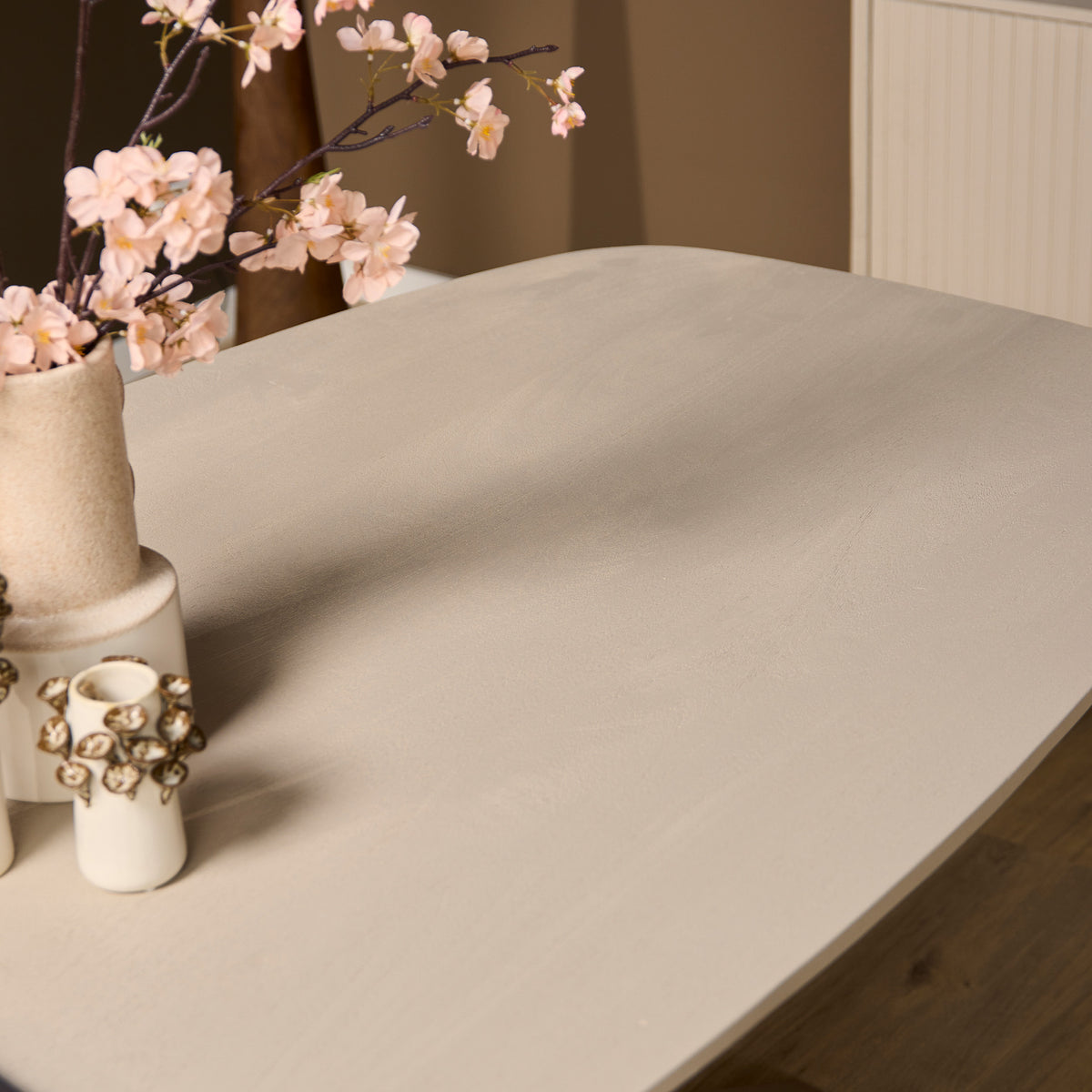 Ovale eettafel met zandkleurig blad, afgeronde hoek en tafelrand in zicht