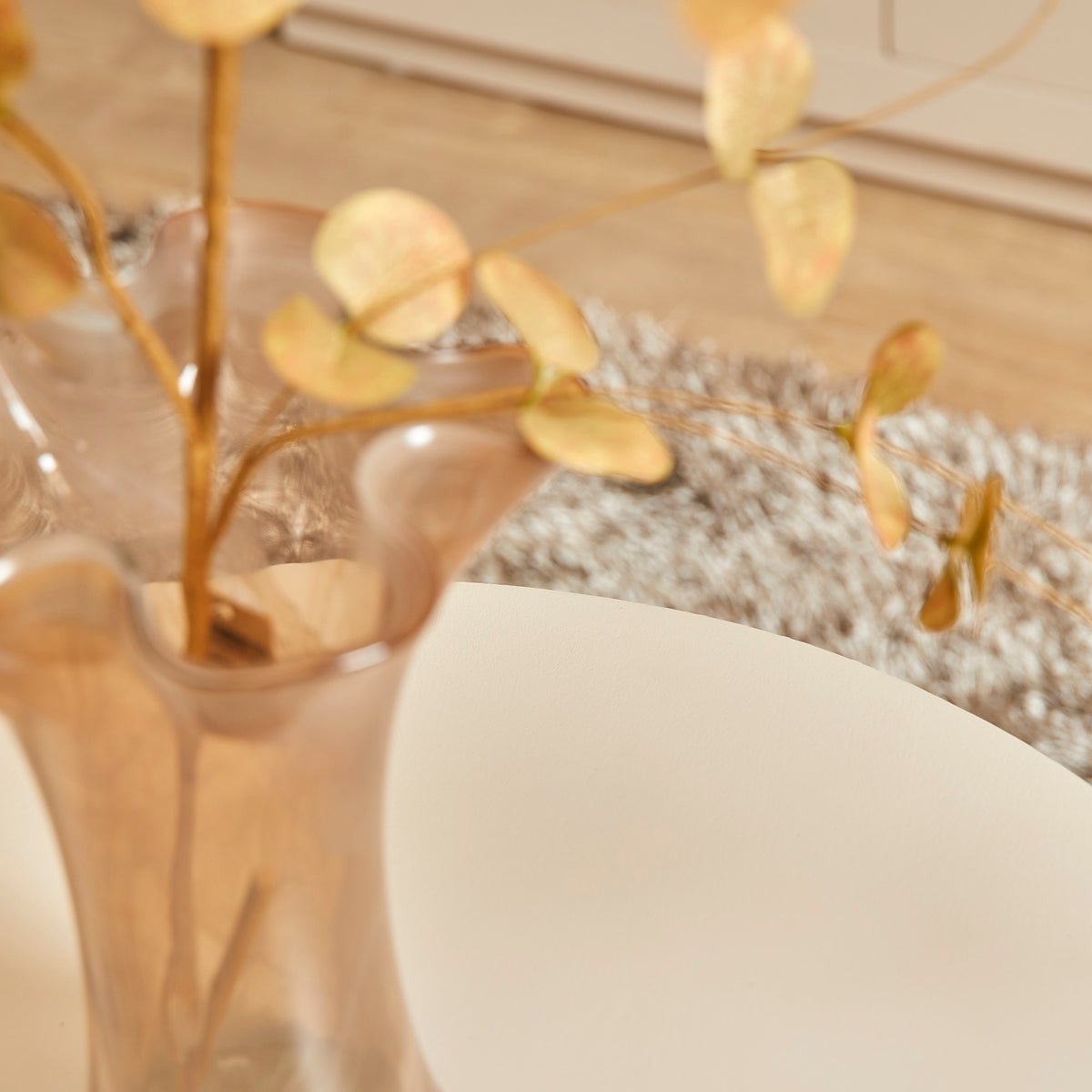 Witte salontafel met rond blad en vaas met bladeren en vlinders