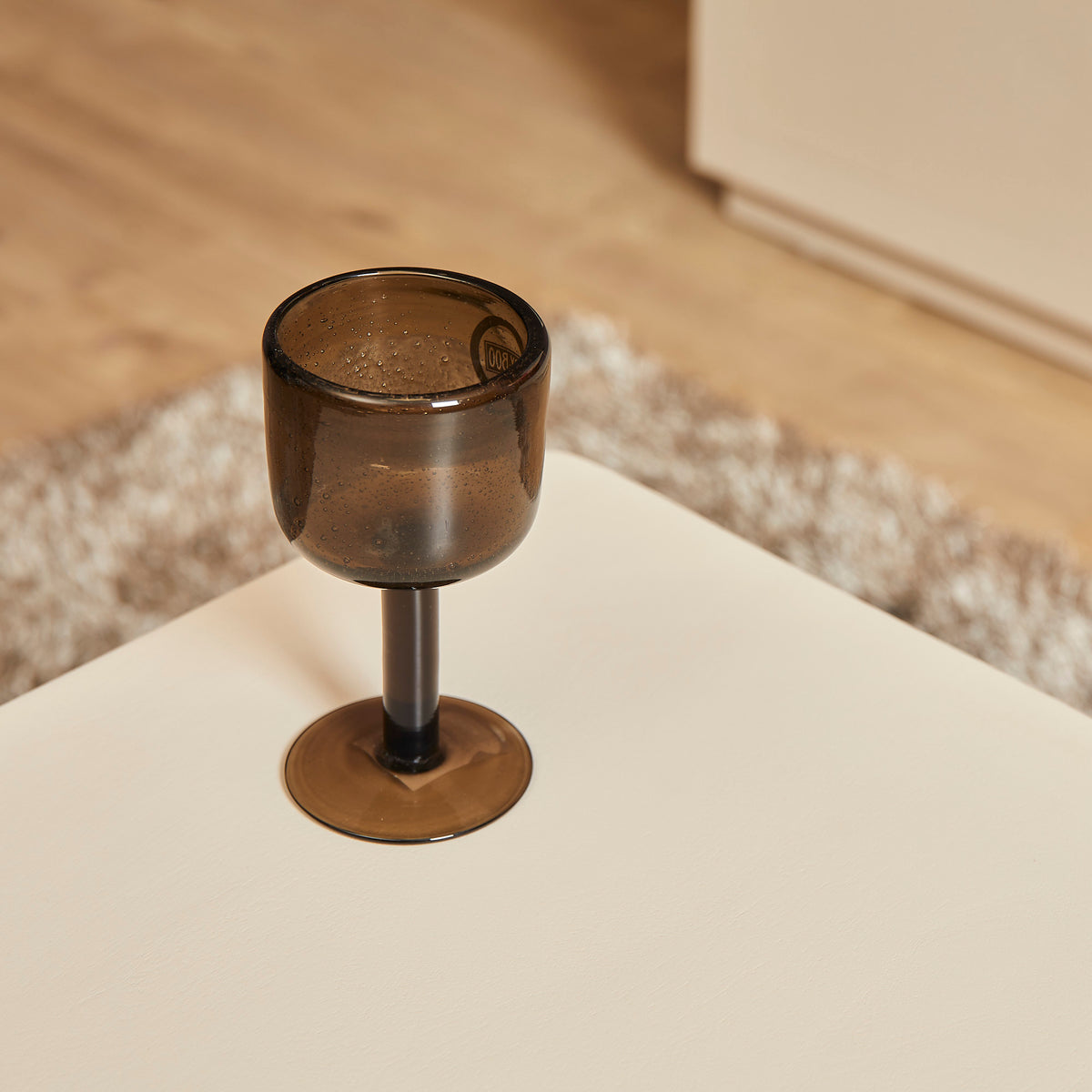 Salontafel Saya met roomwit tafelblad en kaarsglas op het oppervlak
