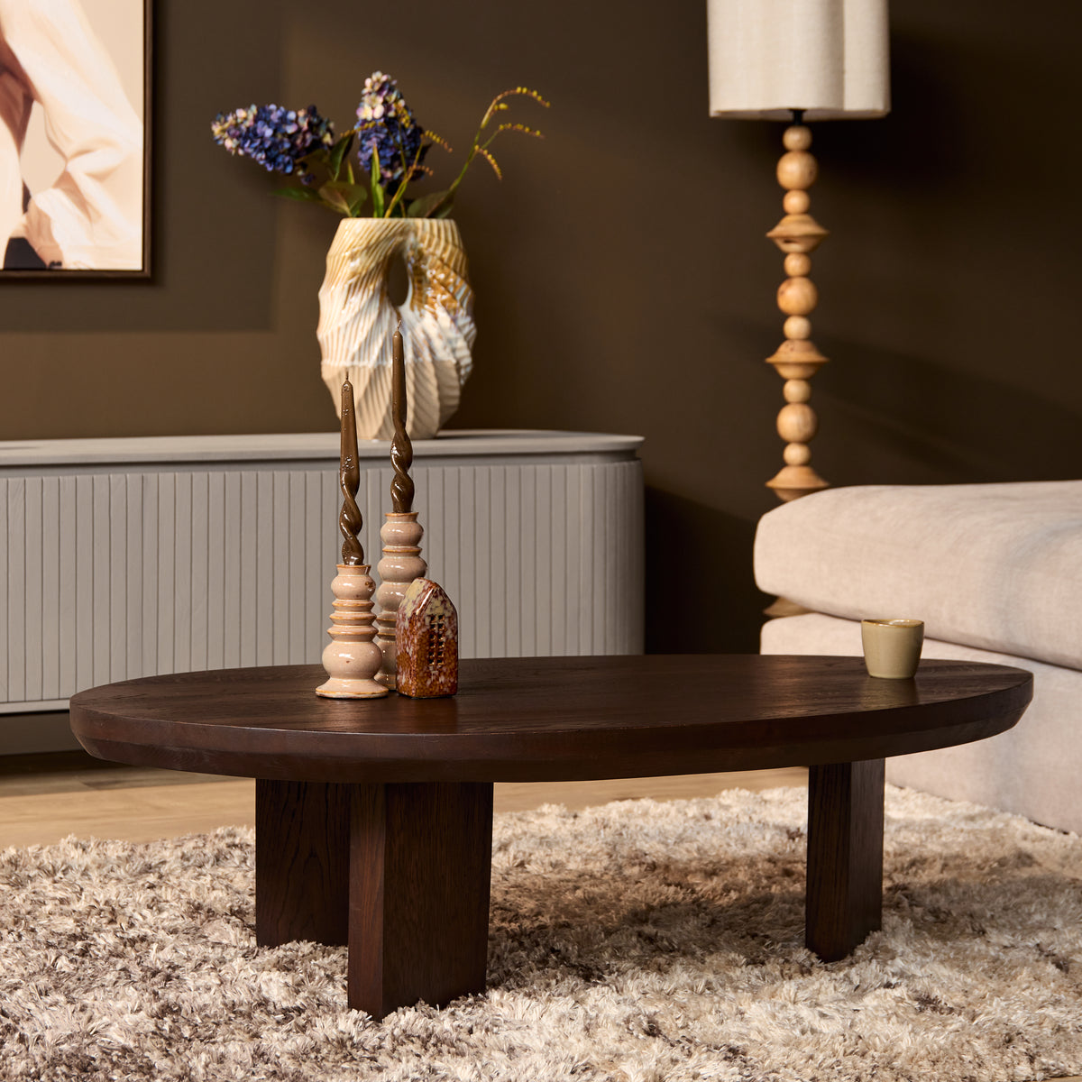 Donkerbruine ronde eikenhouten salontafel met vier korte poten en decor op blad