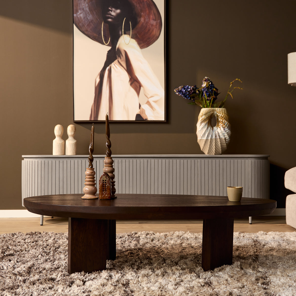Donkerbruine ronde eikenhouten salontafel met vier korte poten en decor op blad