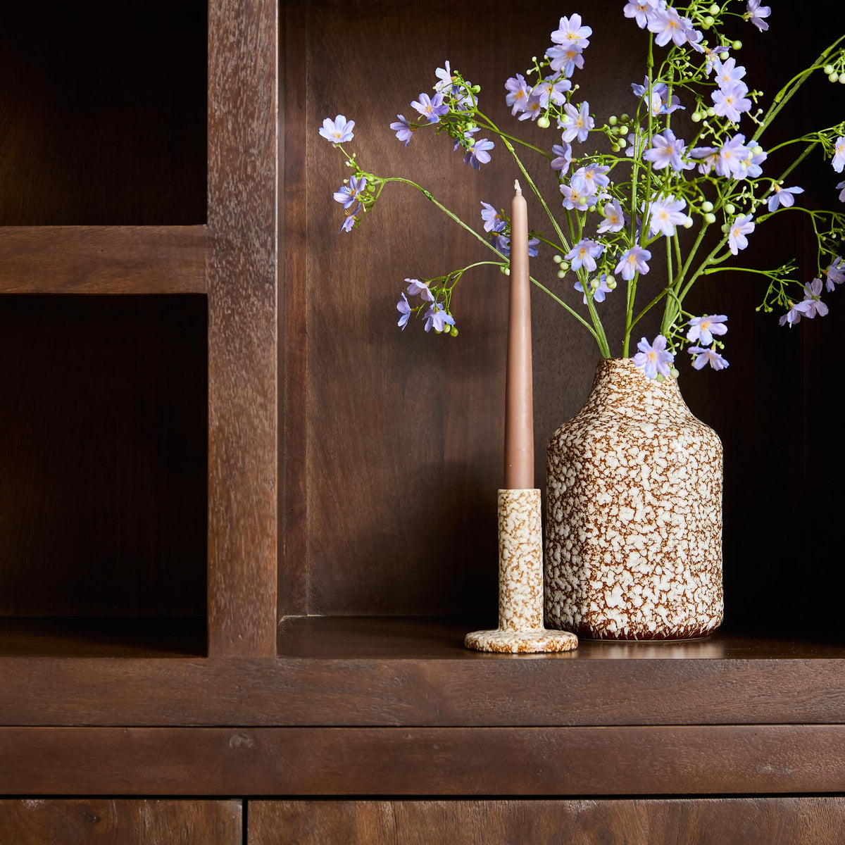Bruine vakkenkast met open vak en decoratieve vaas met bloemen