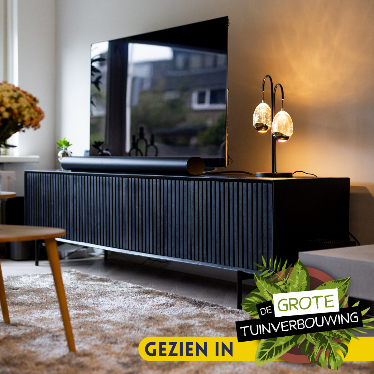 Zwart tv-meubel met geribbelde fronten en lange kast, met twee deuren op poten.
