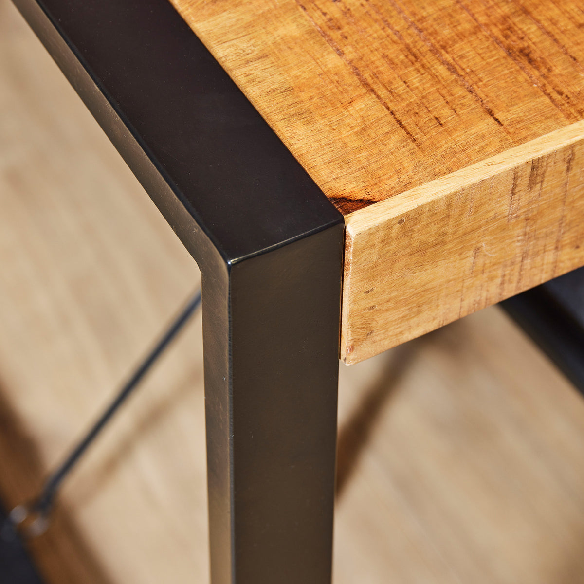 Eettafel met houten blad en zwarte metalen hoek, close-up van bladrand en poot