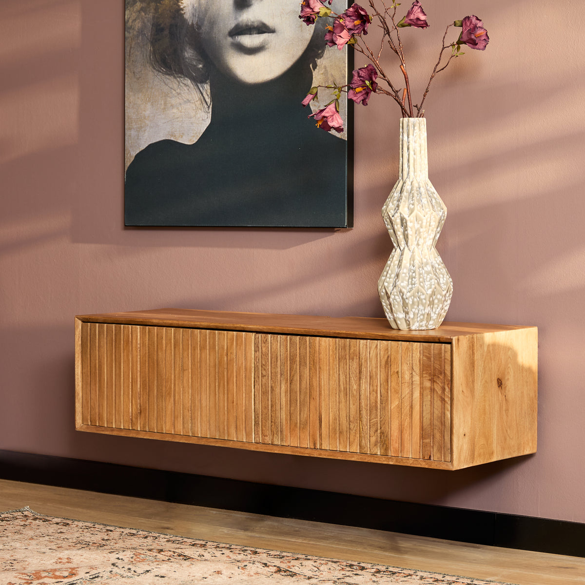 Zwevend tv-meubel van naturel hout met lang rechthoekig front en hoge kastdeur.