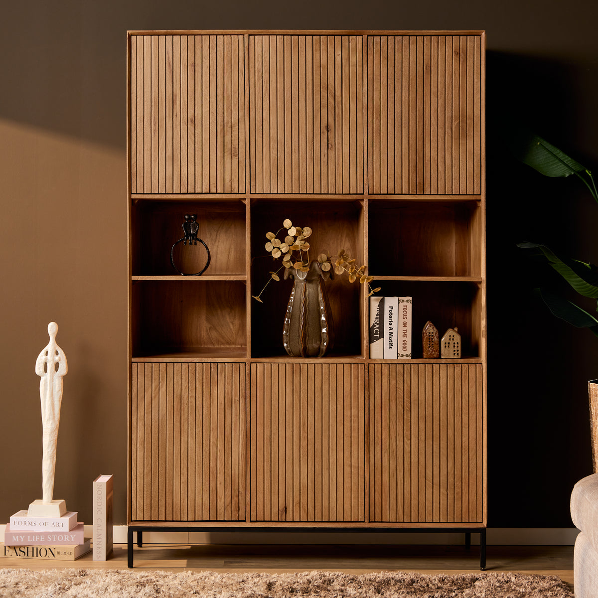 Vakkenkast in naturel hout met open nissen, deurtjes en zwart metalen onderstel.