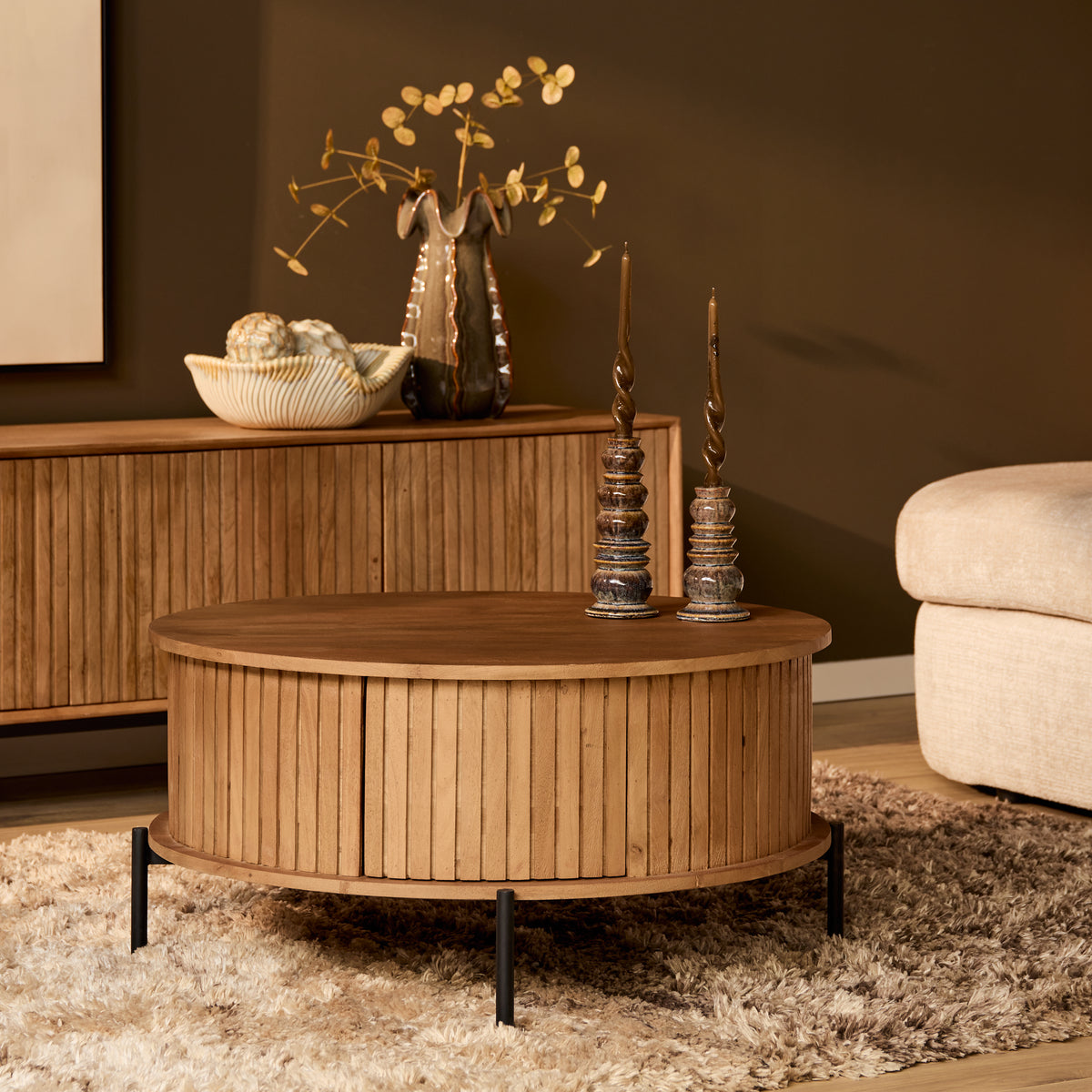 Ronde houten salontafel met ribbenfront en zwart onderstel, naturel blad.