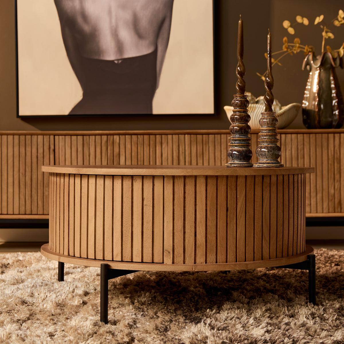 Ronde houten salontafel met smalle latten rondom en zwart metalen poten.