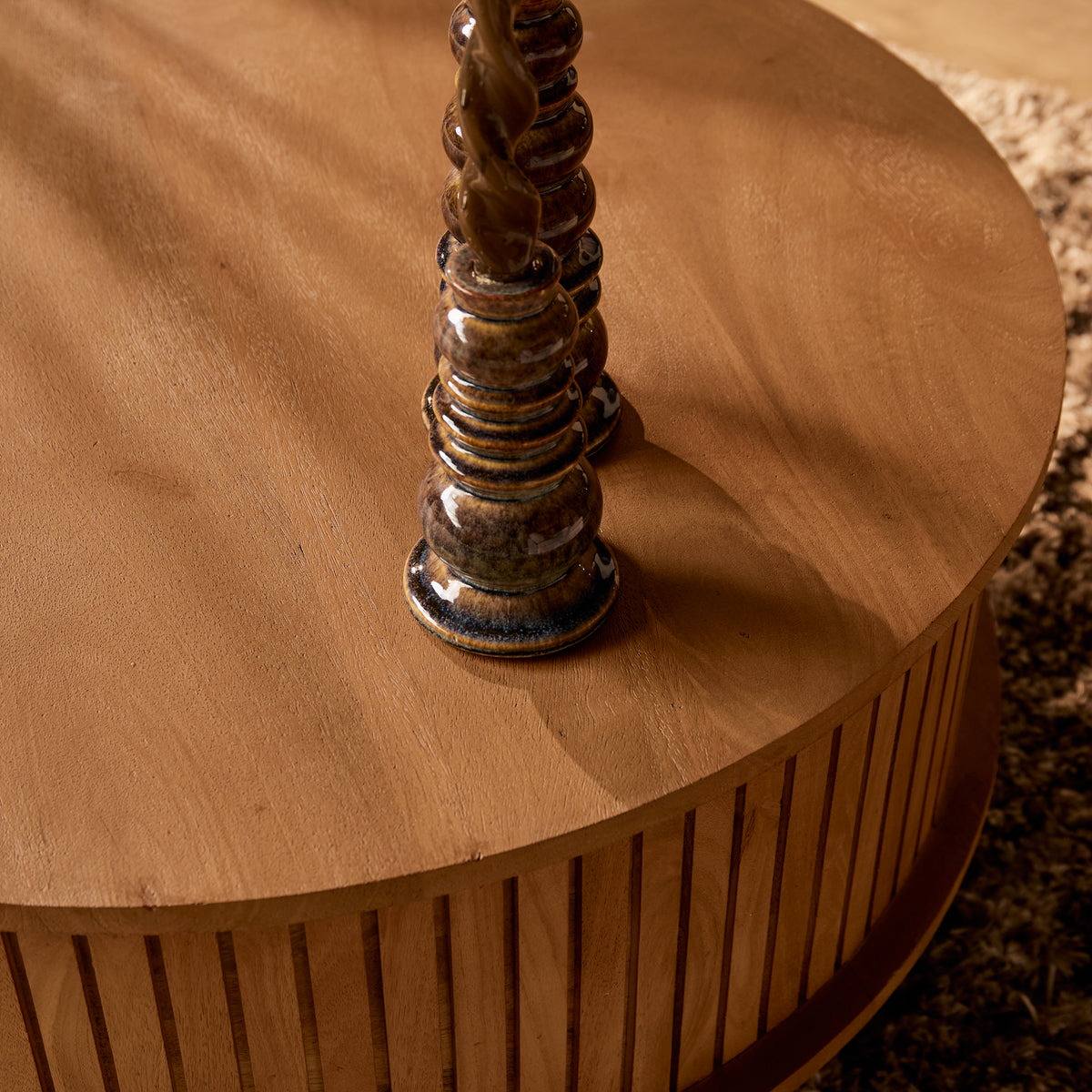 Ronde houten salontafel met rond blad en kaarsenstandaarden.