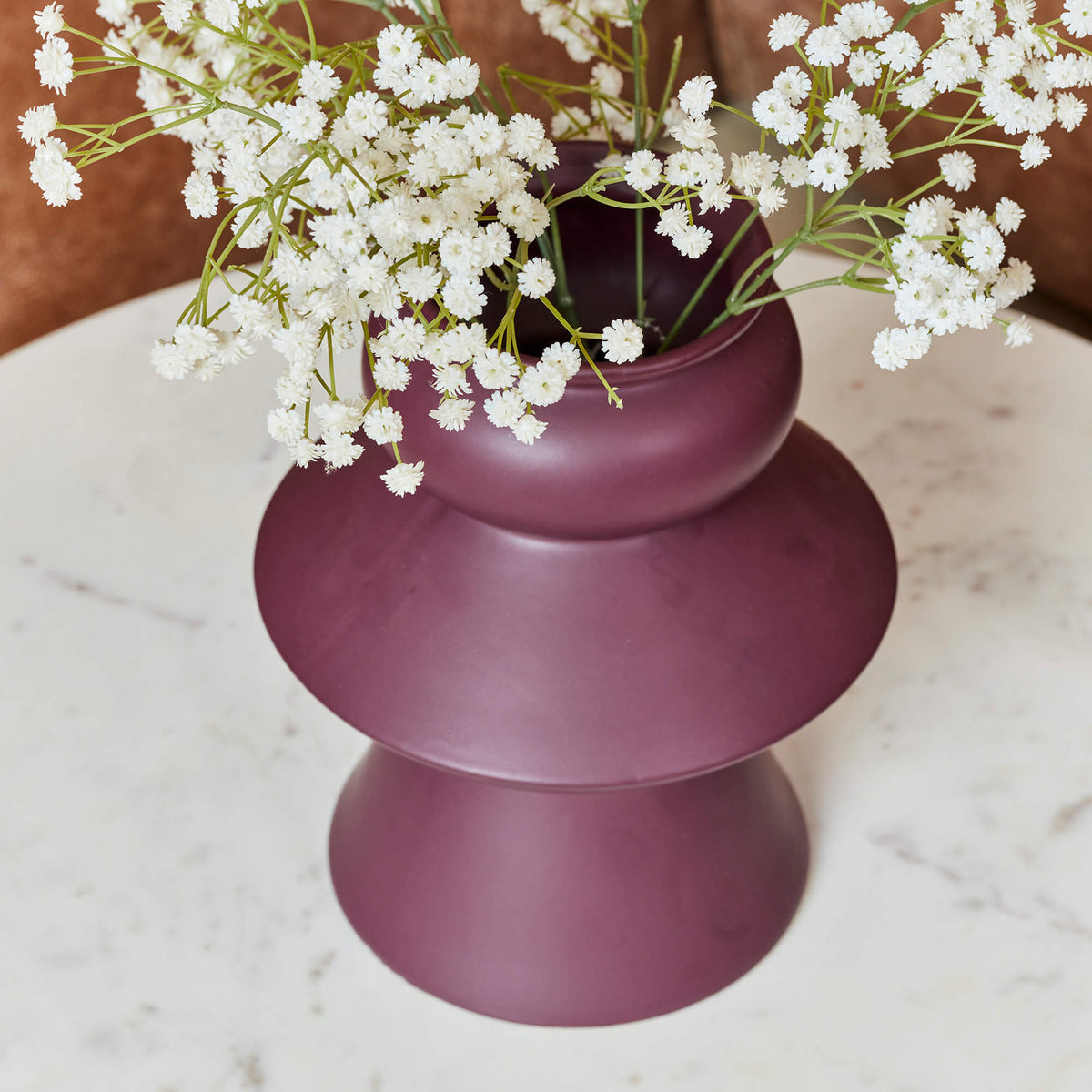 Rond wit marmeren salontafelblad met zwarte metalen rand, met vaas als decoratie