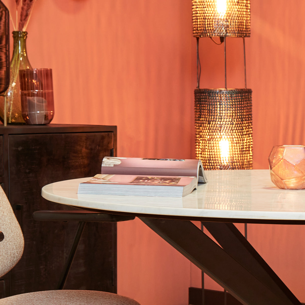Ronde eetkamertafel met wit marmeren blad en zwart onderstel met kruispoten.