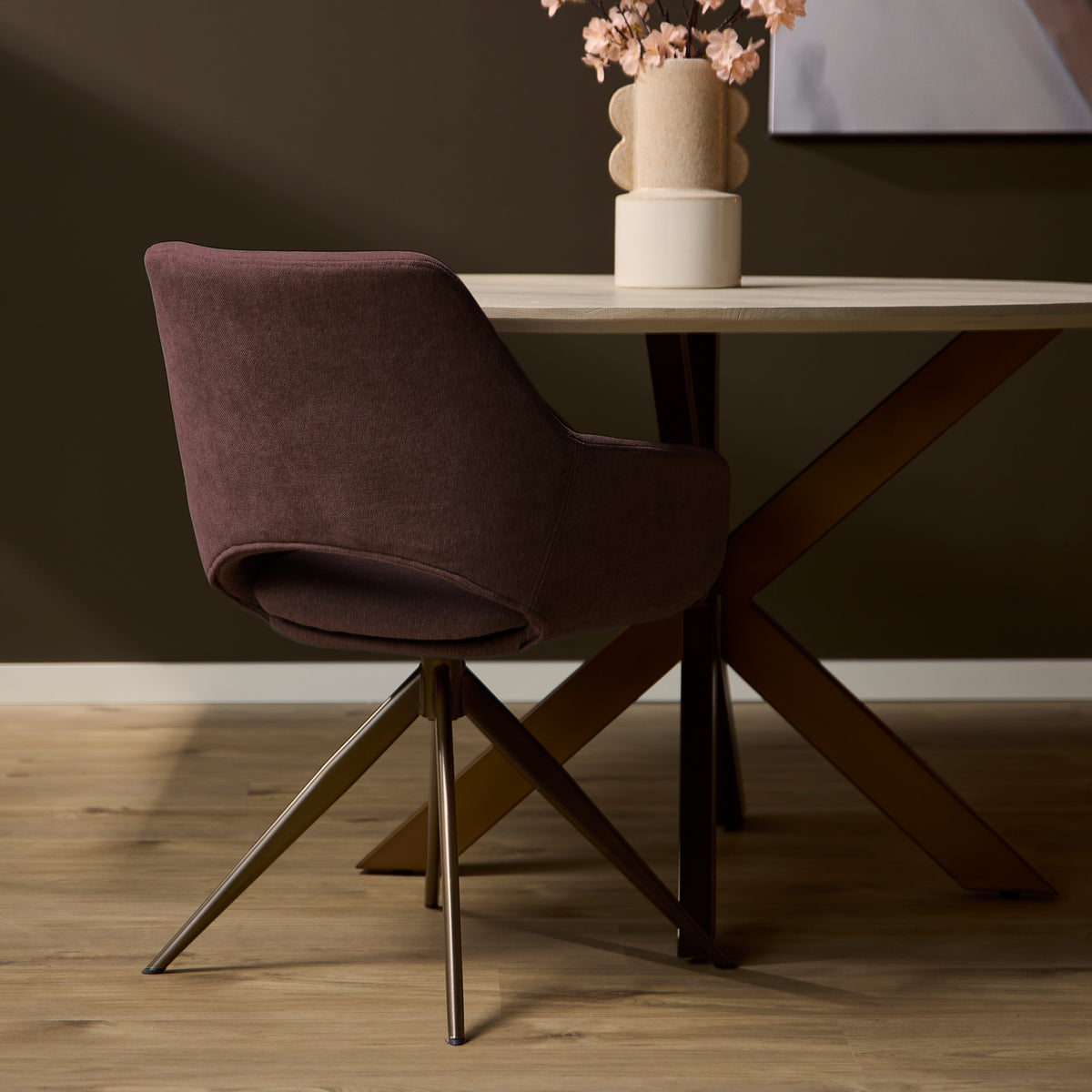 Eetkamerstoel met mauve stoffering en lage rug, op metalen poten met sterbasis.
