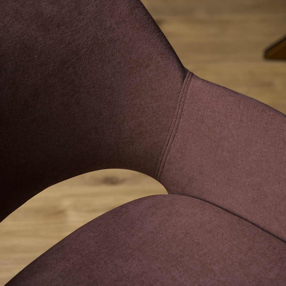 Eetkamerstoel met mauve stoffering, zichtbare naad en gebogen armleuning.
