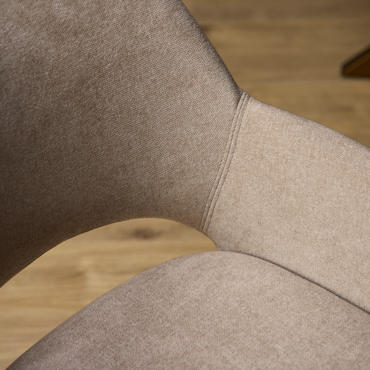 Detail van beige gestoffeerde eetkamerstoel: gebogen rug- en zijkant met stiknaad