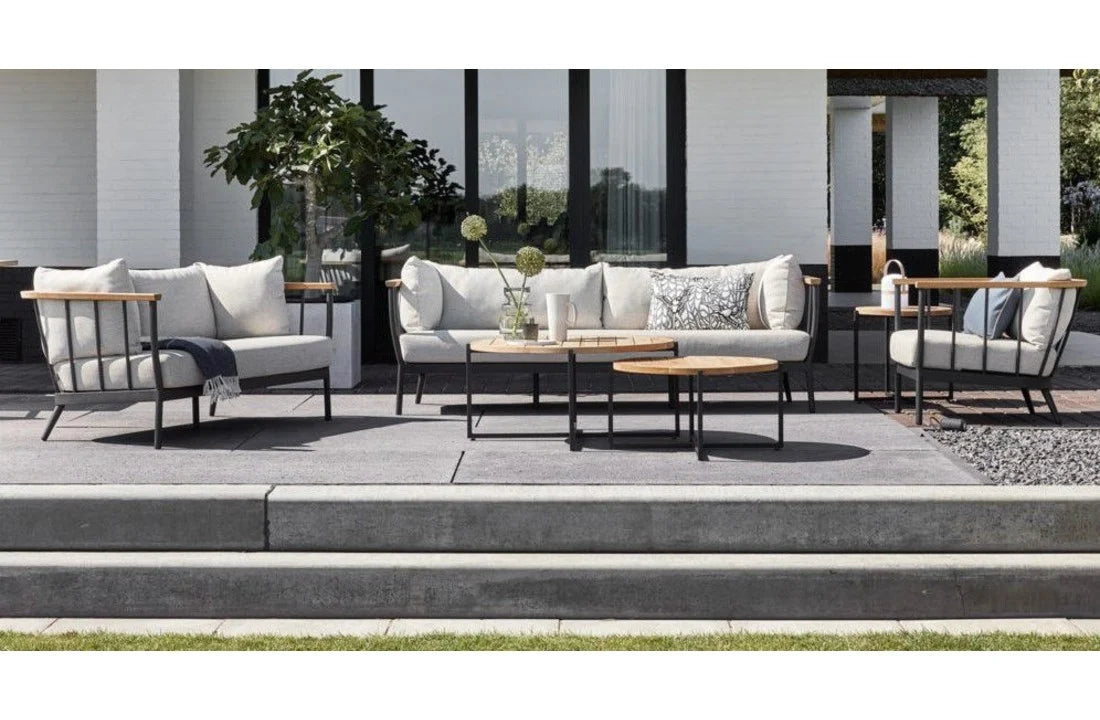 Loungebank met beige zitkussen, zwarte metalen poten en houten armleuningen op terras