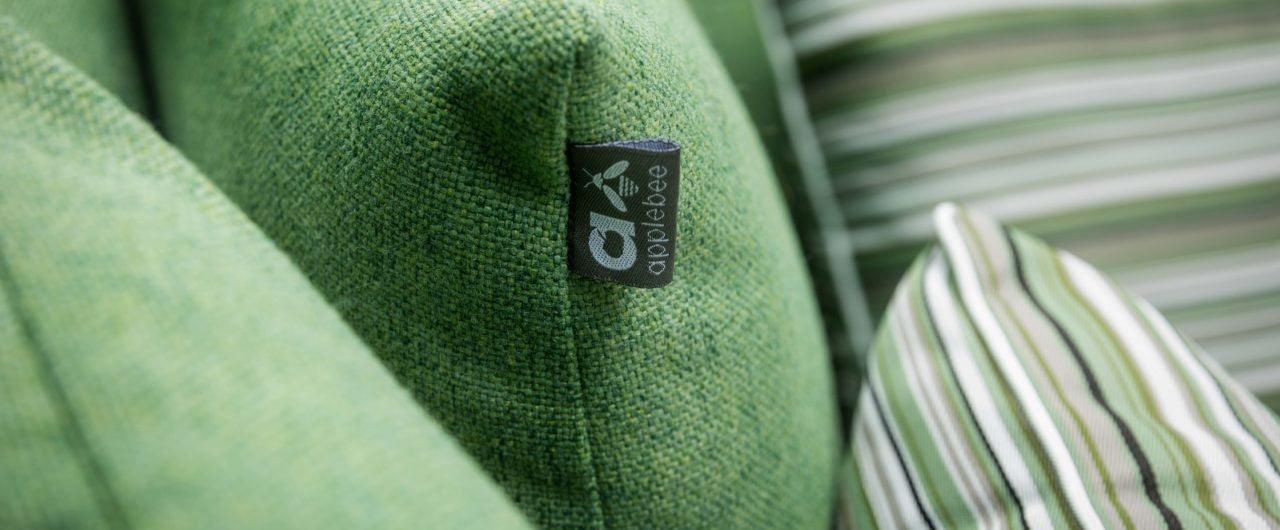 Apple Bee label op groen sierkussen, met detail van gestreepte sloop