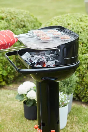 Zwarte houtskoolbarbecue met open deksel en grillrooster met bereiding