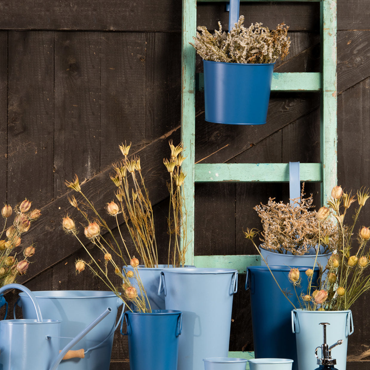 Set van blauwe emmervormige vazen met bloemen, elk met twee hengsels