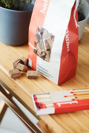 Barbecook aanmaakblokjeszak met bruine houtblokjes op houten plank